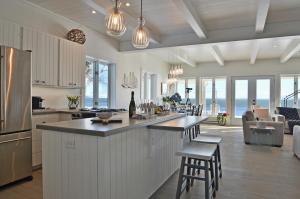 a kitchen and living room with a counter and chairs at Villa et spa - Le coeur de la plage - Charlevoix ! in Saint-Irénée