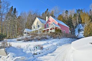 a house in the snow with a road at Villa et spa - Le coeur de la plage - Charlevoix ! in Saint-Irénée