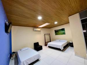 a bedroom with two beds and a wooden ceiling at Hotel Shaday in Leticia