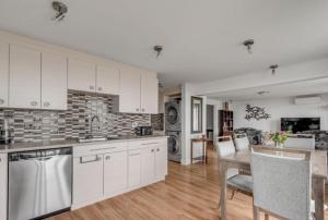 Una cocina con gabinetes blancos y una mesa y sillas. en L'Islet sur le fleuve Condo, en LʼIslet 8 fotos más