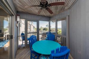 a porch with a blue table and chairs and a ceiling fan at 1120 Duneside Villa by Akers Ellis Rentals in Kiawah Island