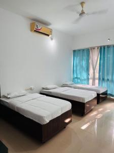 three beds in a room with blue curtains at Elite Stays -Viman Nagar in Pune