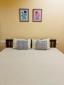 a bed with two pillows and two pictures on the wall at The Vaas Woods - A Garden Homestay in Jaipur
