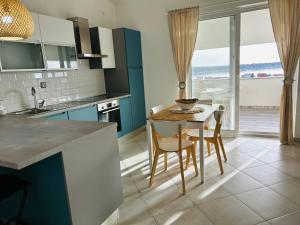 a kitchen with a table and chairs with a view of the ocean at Villa Jadranka Rab apartman Nick in Rab