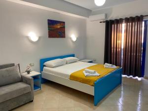 a bedroom with a bed and a couch and a chair at Itaka Hotel Lukova in Lukovë