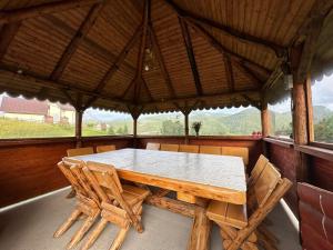 a wooden table and chairs in a porch with a view at Casa Todor Fundata in Fundăţica