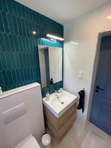 a bathroom with a white sink and a green tiled wall at Azur Corner in Zamárdi +14 photos