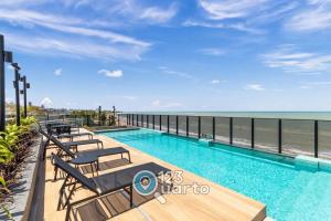 a swimming pool with the ocean in the background at Beach Haus By 123Quarto hospedagem in Tambaú