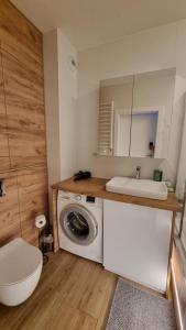 a bathroom with a sink and a washing machine at Apartament Bianco - Aquapark in Rumia