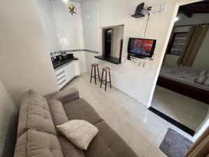 a living room with a couch and a tv at Pousada da Árvore in Boicucanga
