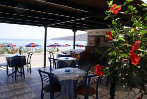 un restaurante con mesas y sillas con vistas al océano en Hotel Eleni Beach, en Livadia