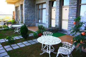patio z dwoma stołami i krzesłami na trawniku w obiekcie Kasauli Castle Resort w mieście Kasauli