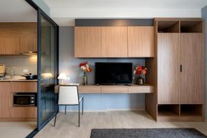 a room with a desk with a tv and a kitchen at Lacasita Luxury 427 Near Huahin Beach in Hua Hin