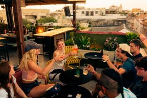 卡塔赫纳Viajero Cartagena - Getsemaní Hostel的一群人坐在屋顶的桌子旁