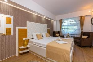 a bedroom with a large bed and a chair at Vujanović Apartments in Sveti Stefan +59 photos