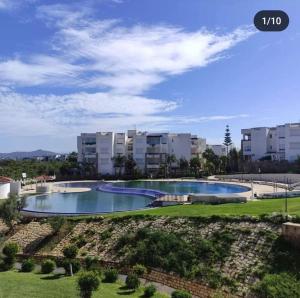 a swimming pool in a park with buildings in the background at Luxe en bord de mère in Restinga Smir