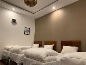 three beds in a room with white sheets at فيلا المنزل in Makkah +19 photos