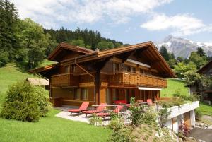 a log cabin with red chairs and a house at Chalet Princess - GRIWA RENT AG in Grindelwald