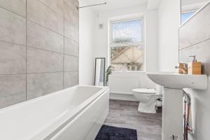a bathroom with a tub and a sink and a toilet at The Major Oak House II Spacious for Family and Teams in Nottingham +36 photos