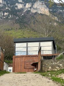 a house with a black roof and a stone wall at Bujtina Sakollari in Poliçan