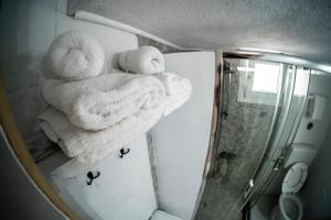 a bathroom with towels on a shelf and a shower at Blackeye Hidden cottage in Nea Potidaea +28 photos