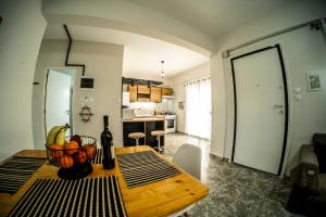 a dining room table with a bowl of fruit and a bottle of wine at Blackeye Hidden cottage in Nea Potidaea