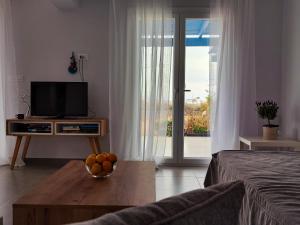 a living room with a television and a bowl of fruit on a table at Amfitriti's Apartment in Naxos Chora