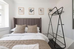 a bedroom with a bed with a tripod next to it at The Romford Oasis - Spacious 4 bedroom escape in Havering atte Bower