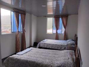 two beds in a room with two windows at Hostal San Felipe in El Peñón