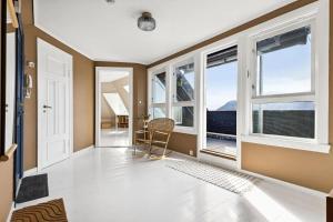 a living room with windows and a table and chairs at Rom i privat loftsleilighet med utsikt in Bergen