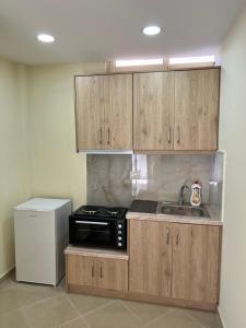 a kitchen with wooden cabinets and a sink and a refrigerator at Saranda View Apartments in Sarandë