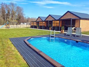 a backyard with a swimming pool and a house at Domki RELAXO Rewal - domki nad morzem z podgrzewanym basenem, placem zabaw i strefą relaksu in Rewal
