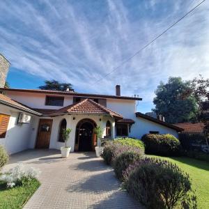 a large white house with a driveway at Hostal La Merced in Villa General Belgrano