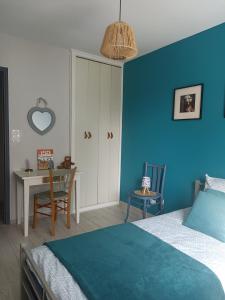 a bedroom with a blue wall with a bed and a table at Entre 2 Châteaux in Onzain
