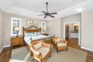 a bedroom with a bed and a chair and a fan at 151 Augusta National Court by Akers Ellis Rentals in Kiawah Island +83 photos