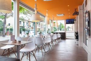 a restaurant with tables and white chairs and windows at Hotel Alex in Lignano Sabbiadoro