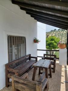 a porch with two wooden benches and a window at La Choza De Mamuyo in Montefrío
