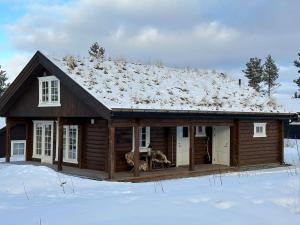 a log cabin with snow on the roof at Sentrumsnær Røroshytte in Røros