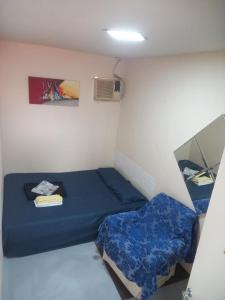 een kleine kamer met een blauw bed en een spiegel bij VILA LEME Casa 11 in Rio de Janeiro