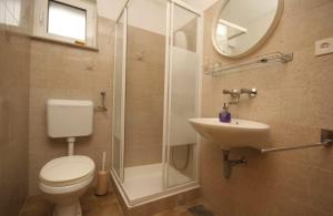 a bathroom with a toilet and a shower and a sink at Apartments Kokotic in Bol