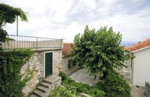 a stone house with a tree and a building at Apartments Kokotic in Bol