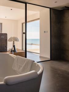 una vasca da bagno in una stanza con vista sulla spiaggia di La villa de la plage a Mauguio