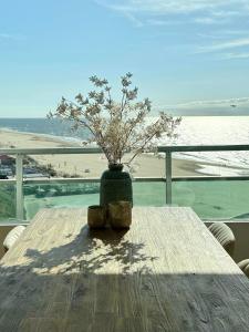 een houten tafel met een vaas met een plant erop bij Sunset Beach in Zandvoort