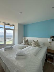 een witte slaapkamer met een groot bed met een raam bij Sunset Beach in Zandvoort