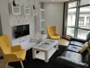 a living room with a couch and chairs and a tv at PISO Bueu Playa in Bueu
