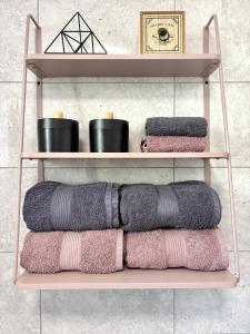 eine Gruppe Handtücher auf einem Regal im Bad in der Unterkunft Wanderlust Home Pink, Rasnov Apt for 4, Wifi and Free Parking in Râșnov
