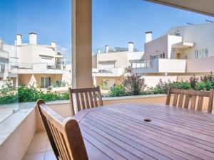 ein Holztisch und Stühle auf einem Balkon mit Gebäuden in der Unterkunft Casa Aromas do Mar, Burgau in Burgau