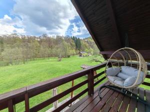 a wicker chair sitting on the porch of a cabin at Căsuța dintre Meri in Moieciu de Jos