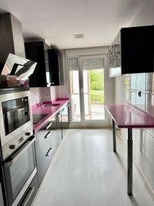 a kitchen with pink counters and a large window at Apartamento Picos de Europa in Comillas +8 photos