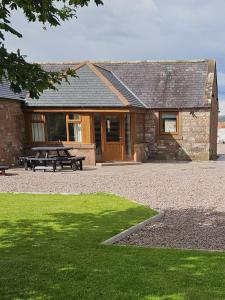 a stone house with a picnic table and a bench at Stanloch Cottage - rural, well equipped, games room, EV in Dumfries